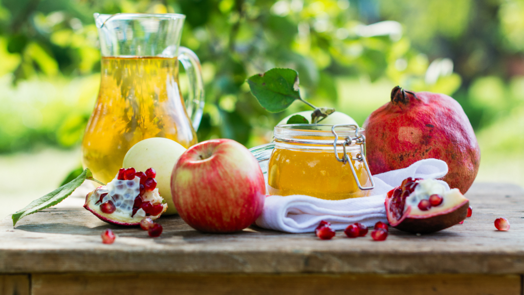 Photo showing fresh organic honey in  a jar with apples and other fruit from a bountiful homestead harvest. 