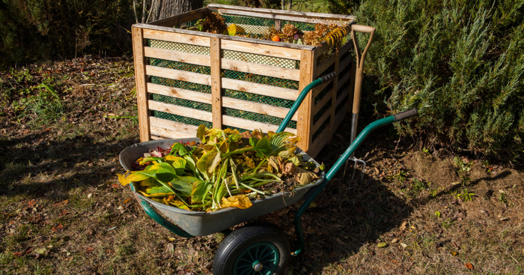 An open DIY compost bin made from scrap wood and lined with garden mesh, perfect for basic backyard composting.