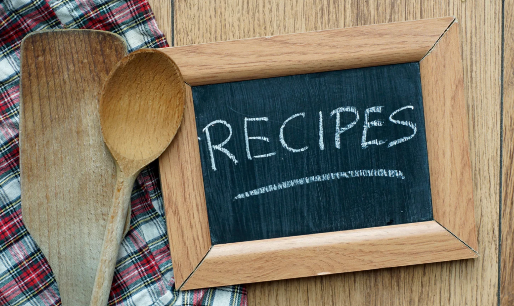 A wood-framed chalk board showing "Recipes" with wooden spoon.