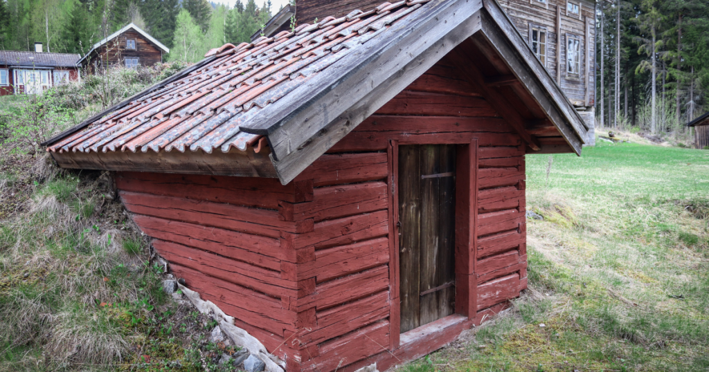 Outside entrance to a rustic root cellar built into a raised part of a homestead property.