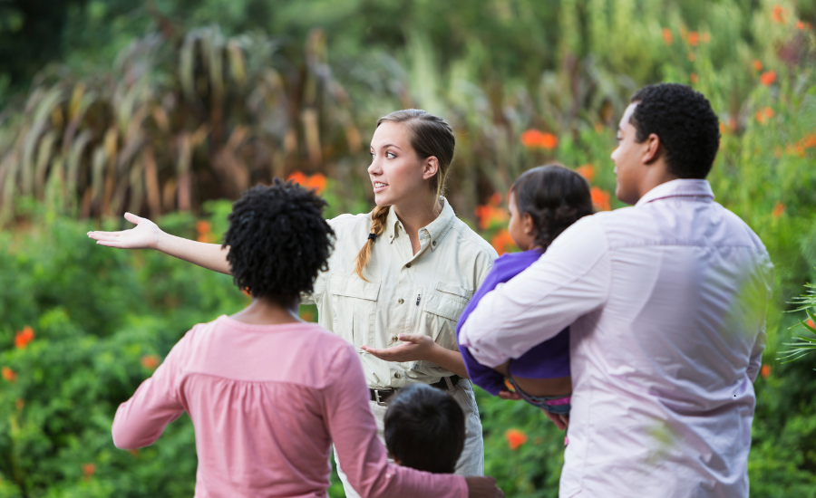 A woman is giving a homestead farm tour to a family of three.