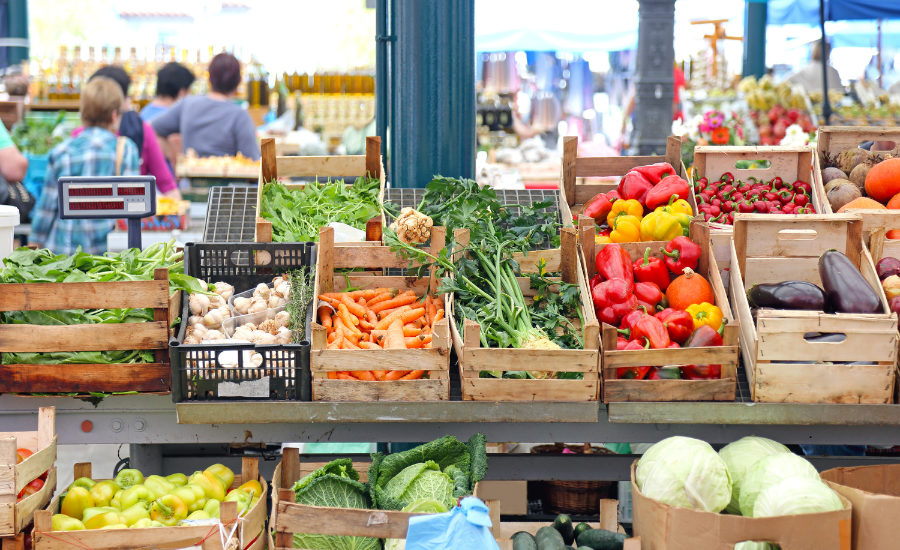 Photo of a sprawling farmer's market with organic produce in wood bins.