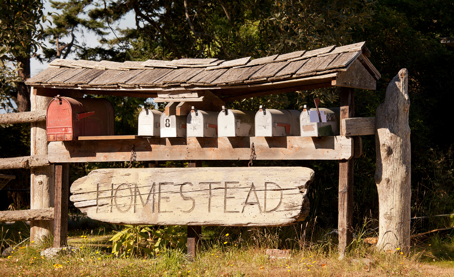 A rustic homestead sign with mailboxes.