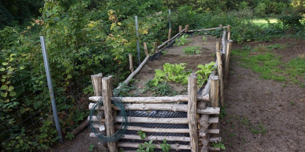 An example of a DIY raised bed garden made from interlocked reclaimed wood posts, lined and filled with soil.